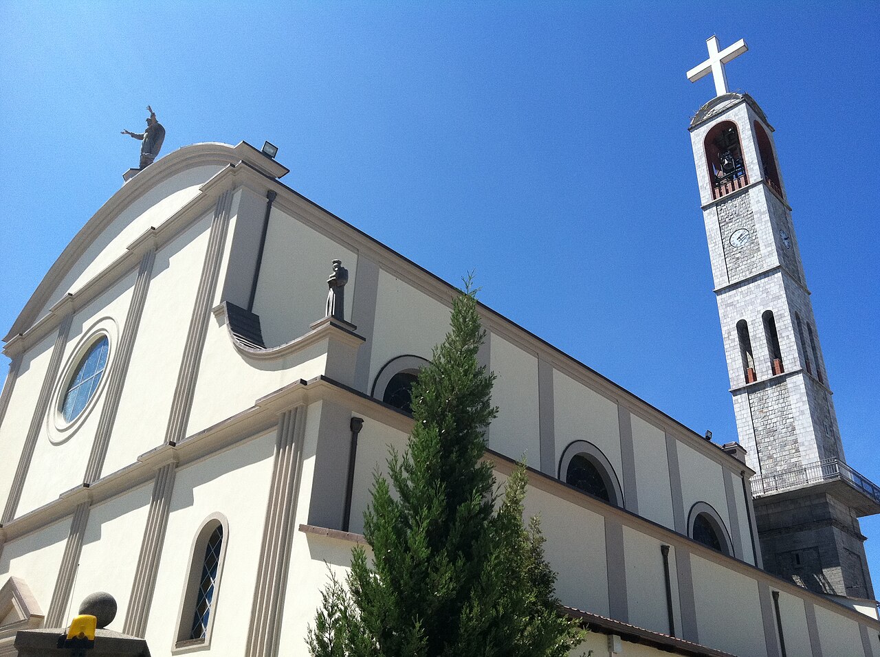 The Franciscan Church of Shkodra with its tall stone bell tower against a blue sky