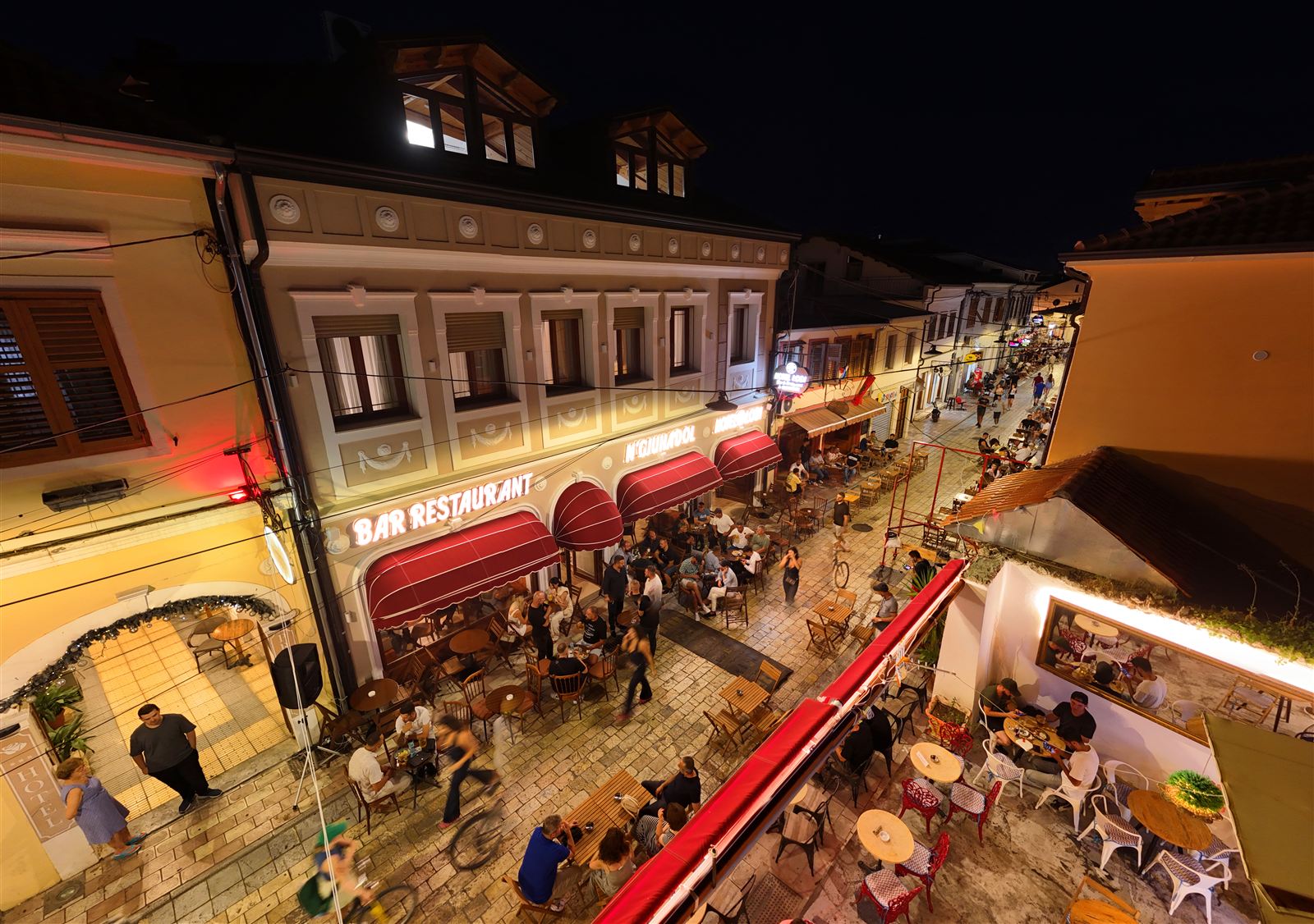 Evening cafe and restaurant terraces on a street in the Gjuhadol quarter of Shkodra