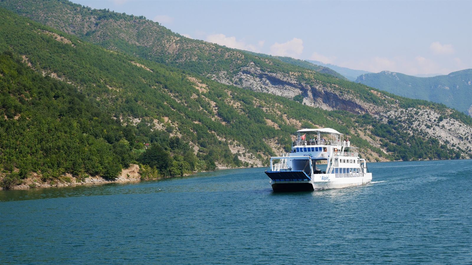 The Lake Koman ferry crossing the canyon between steep green mountainsides in northern Albania