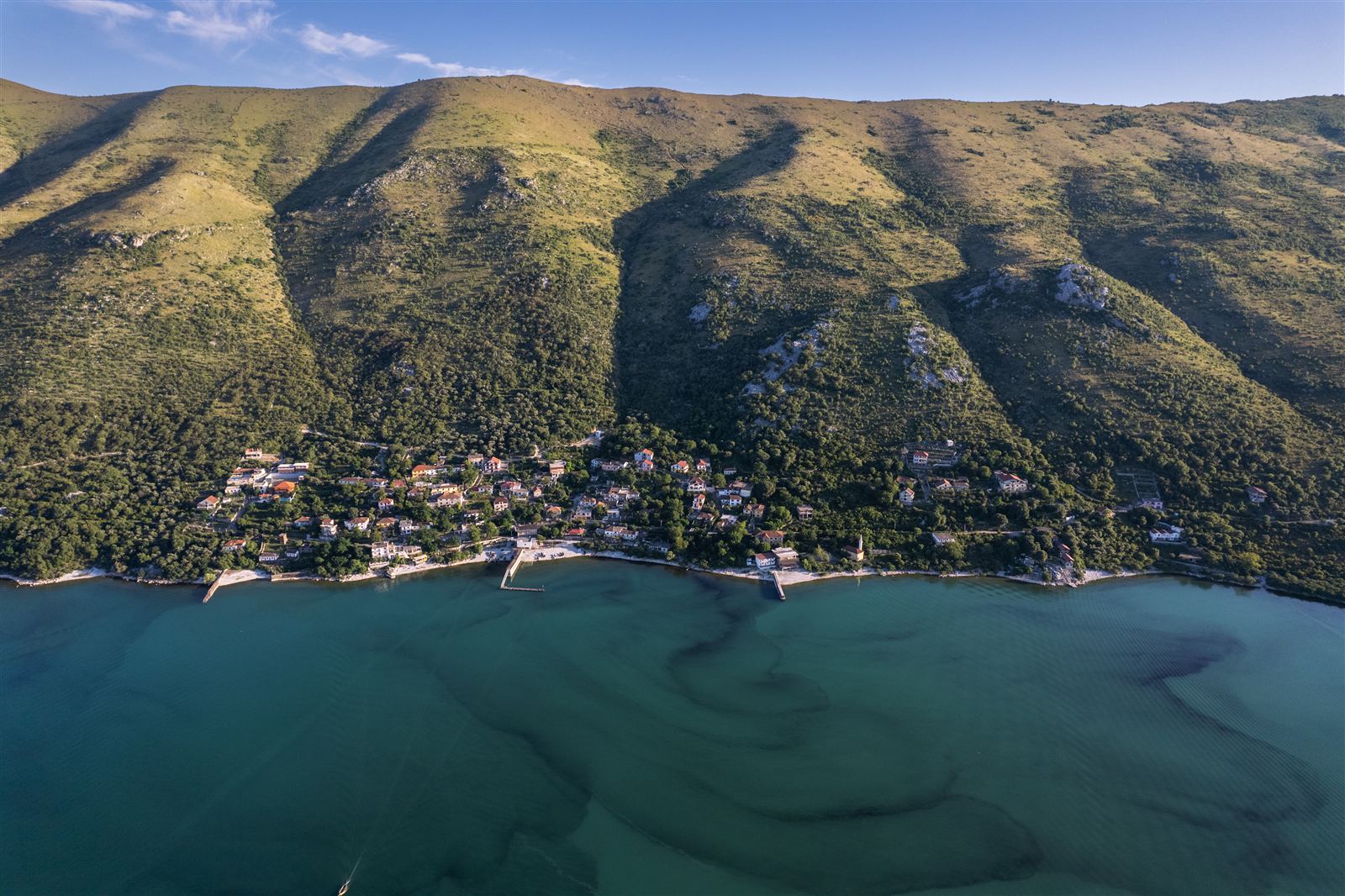 Aerial view of Zogaj village on the green mountainous shore of Lake Shkodra